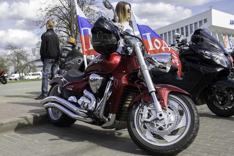 Červená motorka, vlajky, žena stojí pri motorke